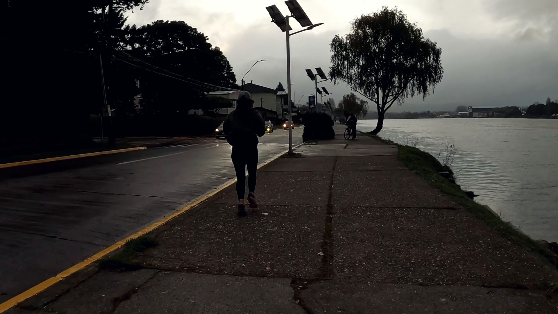A runner seen from behind on a seaside path on a grey northern morning.